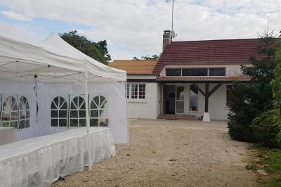 Cuisine simple avec évier en inox, étagères mobiles, cuisinière blanche et sol en carrelage rouge.