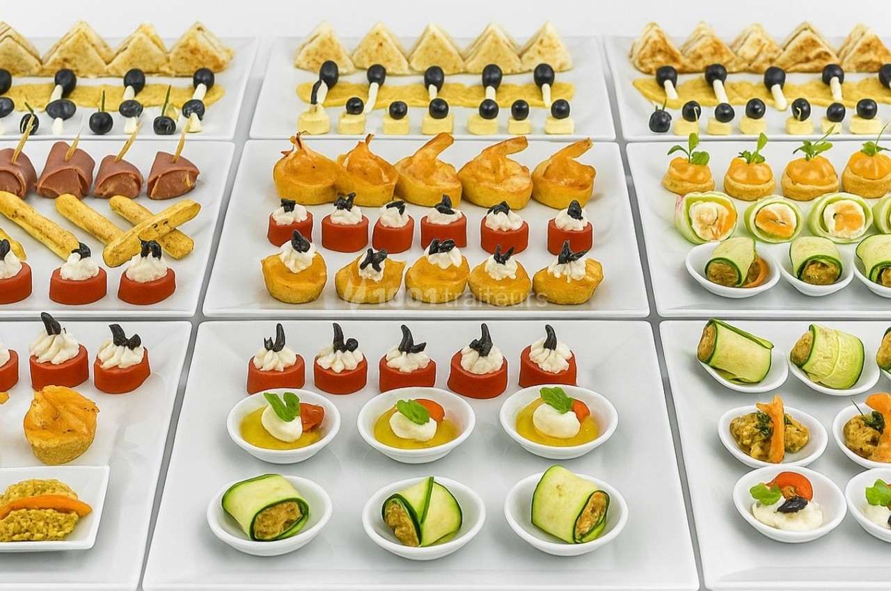 Plateau de canapés variés comprenant légumes, fromages, viandes et poissons, présentés de manière soignée.