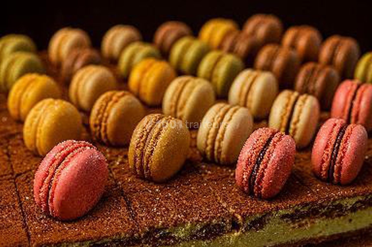Assortiment de macarons colorés disposés en rangées sur un fond de gâteau au chocolat.
