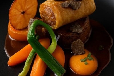 Assiette gastronomique avec tranches de poisson, agrumes, radis, croustillant décoratif et points de sauce balsamique.