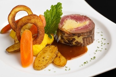 Assiette gastronomique avec tranches de poisson, agrumes, radis, croustillant décoratif et points de sauce balsamique.