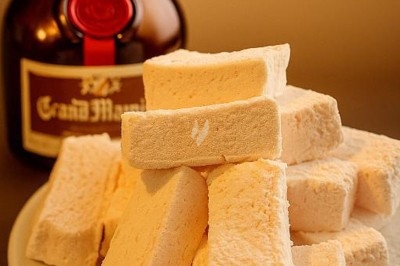 Assiette gastronomique avec tranches de poisson, agrumes, radis, croustillant décoratif et points de sauce balsamique.