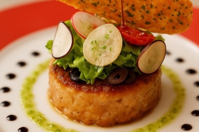 Assiette gastronomique avec tranches de poisson, agrumes, radis, croustillant décoratif et points de sauce balsamique.