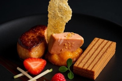 Assiette gastronomique avec tranches de poisson, agrumes, radis, croustillant décoratif et points de sauce balsamique.