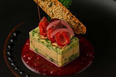 Assiette gastronomique avec tranches de poisson, agrumes, radis, croustillant décoratif et points de sauce balsamique.