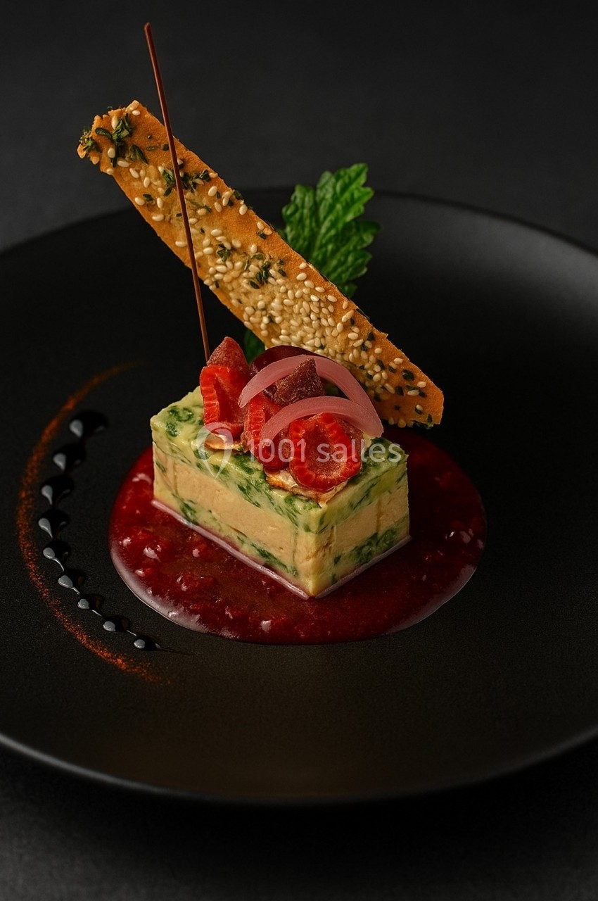 Plat gastronomique composé d'une terrine aux herbes, framboises, oignons marinés, tuile au sésame et coulis rouge.