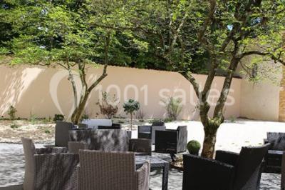 Salle de conférence moderne avec estrade, pupitre transparent, chaises blanches et rangées de sièges vides.