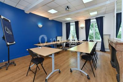 Salle de conférence moderne avec estrade, pupitre transparent, chaises blanches et rangées de sièges vides.