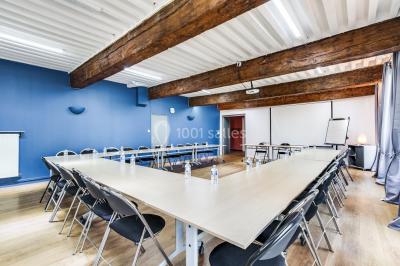 Salle de conférence moderne avec estrade, pupitre transparent, chaises blanches et rangées de sièges vides.