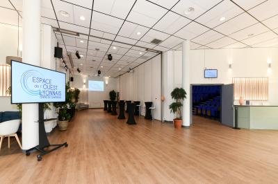 Salle de conférence moderne avec estrade, pupitre transparent, chaises blanches et rangées de sièges vides.