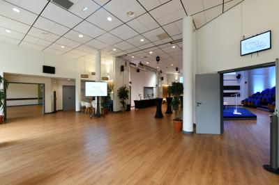 Salle de conférence moderne avec estrade, pupitre transparent, chaises blanches et rangées de sièges vides.