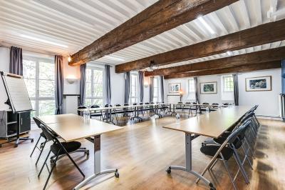 Salle de conférence moderne avec estrade, pupitre transparent, chaises blanches et rangées de sièges vides.