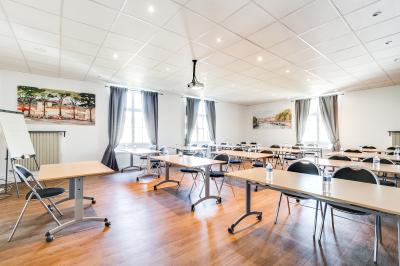 Salle de conférence moderne avec estrade, pupitre transparent, chaises blanches et rangées de sièges vides.