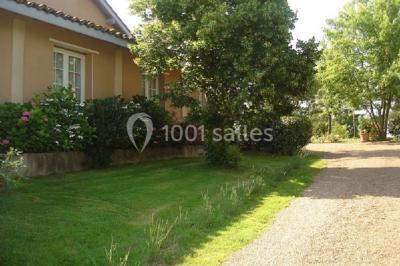 Jardin avec pelouse, arbres et pot en terre cuite au premier plan, éclairé par une lumière douce en fin de journée.