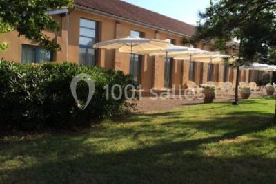 Jardin avec pelouse, arbres et pot en terre cuite au premier plan, éclairé par une lumière douce en fin de journée.