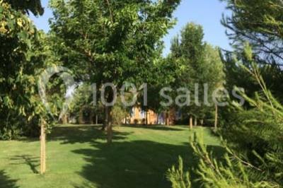 Jardin avec pelouse, arbres et pot en terre cuite au premier plan, éclairé par une lumière douce en fin de journée.