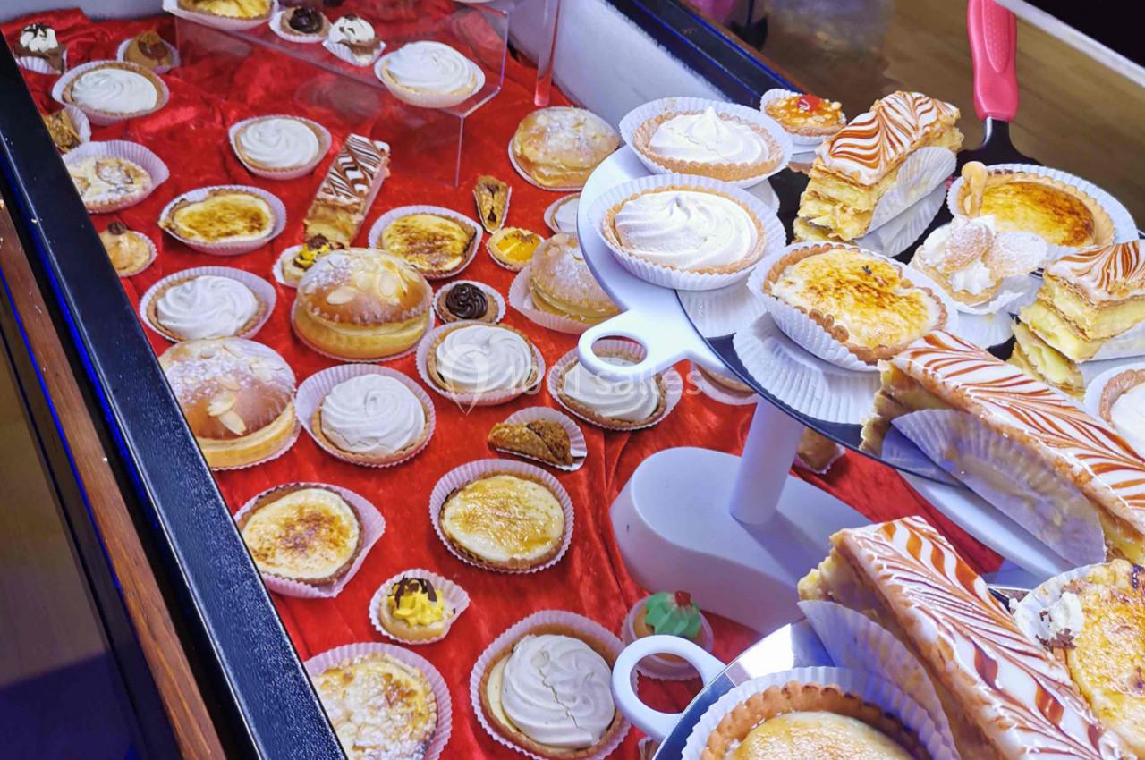 Vitrine présentant une variété de pâtisseries sur un fond rouge, incluant tartes, éclairs et gâteaux individuels.
