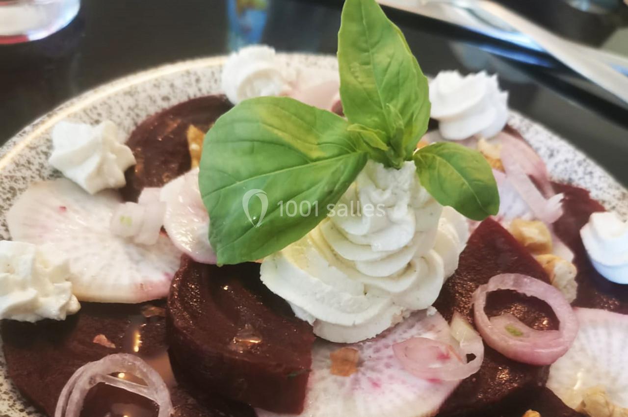 Tranches de betterave garnies de fromage frais, rondelles d'oignon, noix concassées et feuille de basilic.