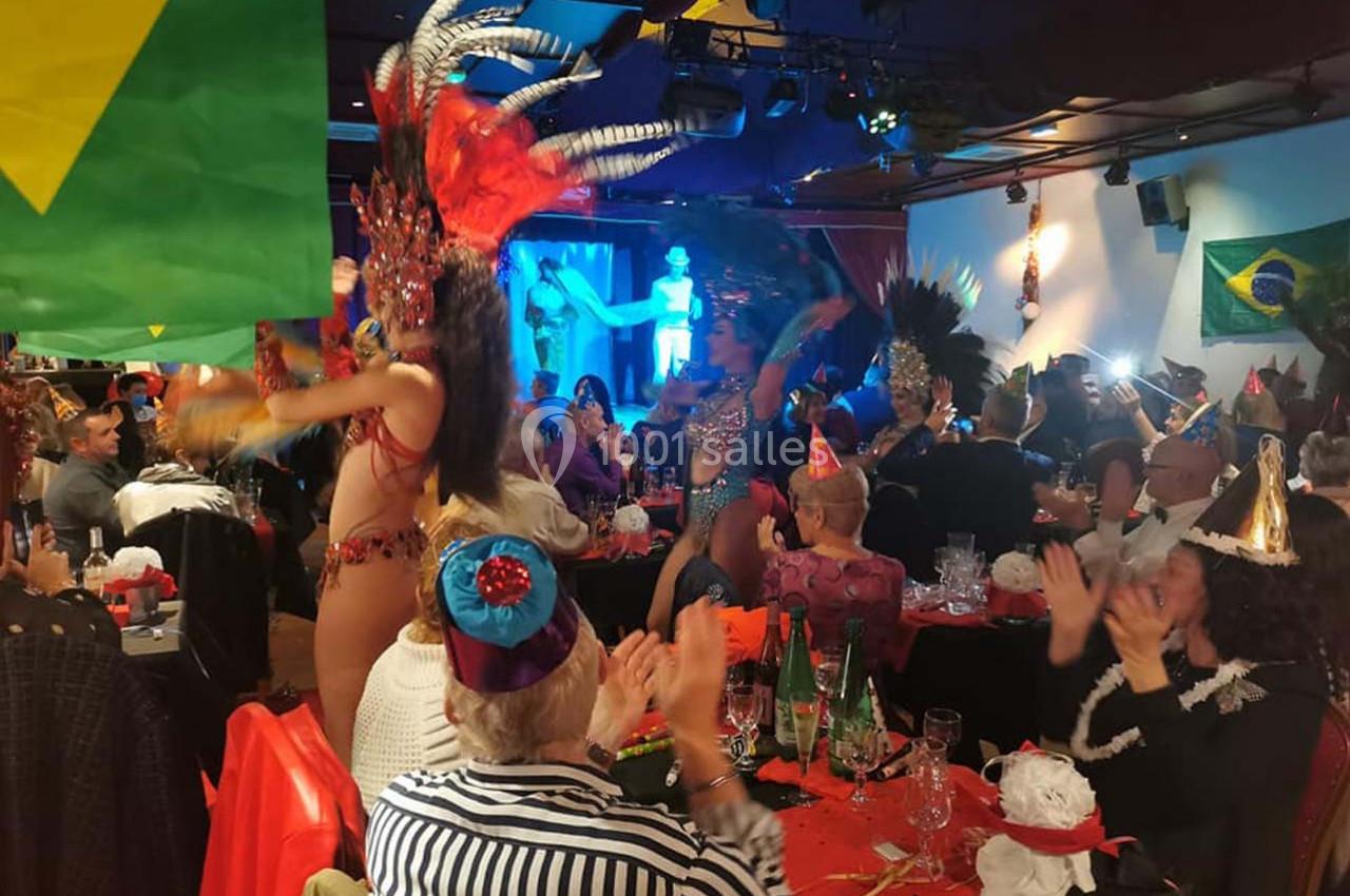 Danseuse en costume coloré se produisant sur scène lors d'une fête avec des spectateurs applaudissant, décorée de drapeaux…