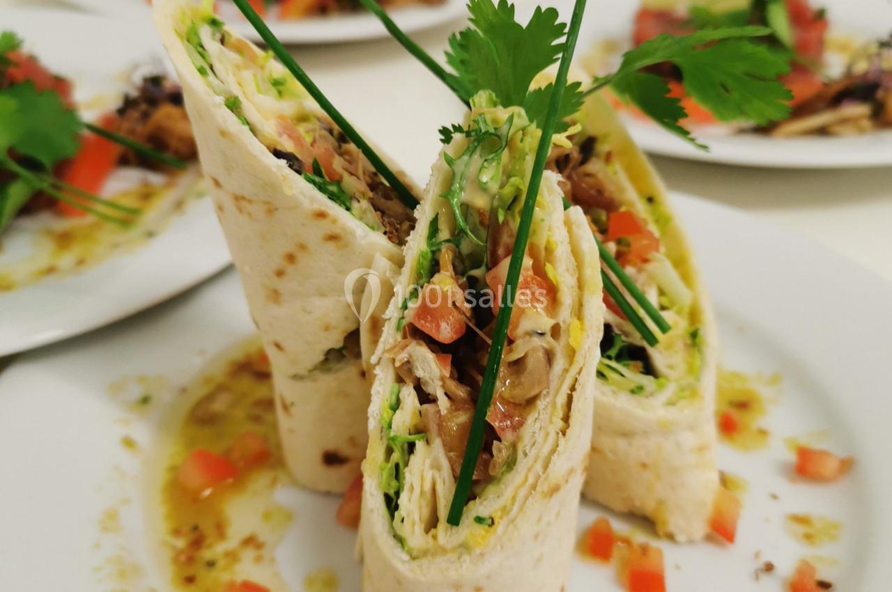 Wraps garnis de légumes frais, herbes et sauce, présentés en tranches sur une assiette blanche.