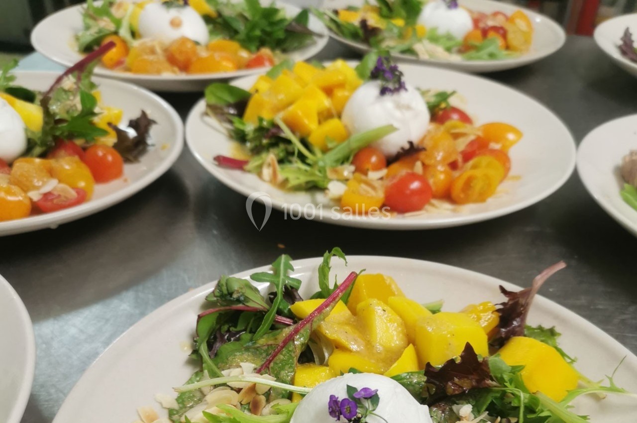 Assiettes de salades colorées garnies de burrata, tomates cerises, mangue et feuilles de salade, décorées de fleurs…