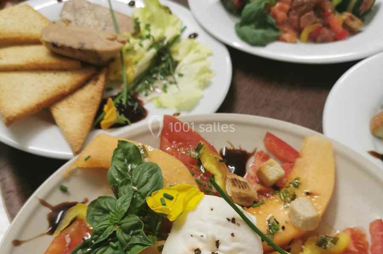 Assiette de salade composée avec melon, tomate, mozzarella, herbes fraîches et décoration florale, accompagnée de toasts et…