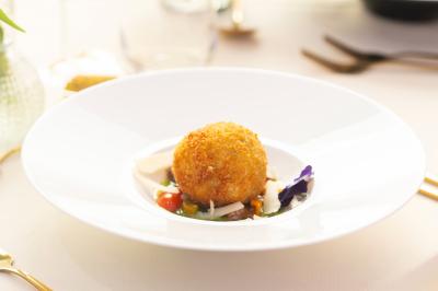 Macaron rose garni de crème, décoré d'une fraise, d'une framboise, d'une fleur comestible et de coulis rouge.