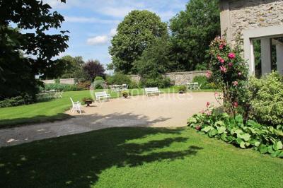 Chaises blanches en plastique disposées sur une pelouse ombragée, avec une tente et un jardin en arrière-plan.