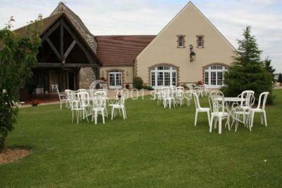Chaises blanches en plastique disposées sur une pelouse ombragée, avec une tente et un jardin en arrière-plan.