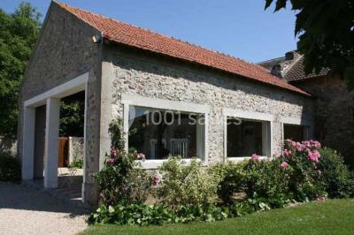 Chaises blanches en plastique disposées sur une pelouse ombragée, avec une tente et un jardin en arrière-plan.
