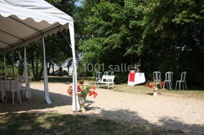 Chaises blanches en plastique disposées sur une pelouse ombragée, avec une tente et un jardin en arrière-plan.