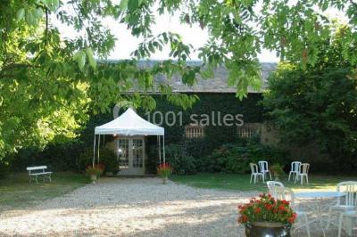 Chaises blanches en plastique disposées sur une pelouse ombragée, avec une tente et un jardin en arrière-plan.