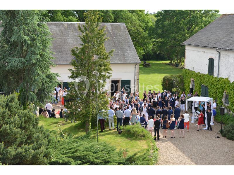 Groupe de personnes rassemblées dans une cour extérieure, entourée de bâtiments et de verdure.