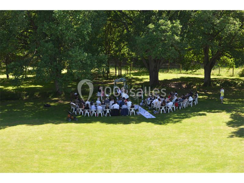 Cérémonie en plein air avec des invités assis en cercle sous des arbres dans un cadre verdoyant.