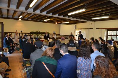 Un groupe de personnes assises dans une salle en bois assistent à une cérémonie officielle.