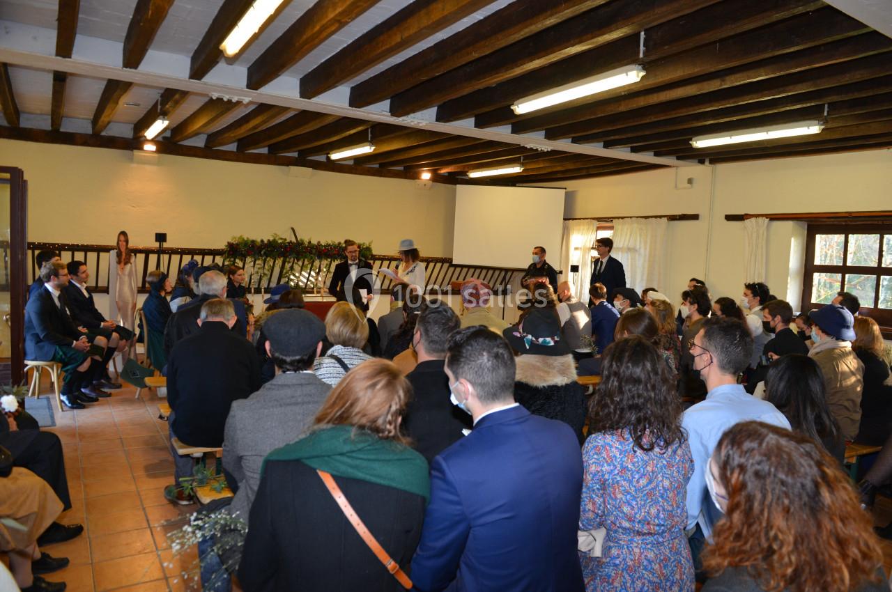 Un groupe de personnes assises dans une salle en bois assistent à une cérémonie officielle.