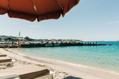 Chambre lumineuse avec lit double, fauteuils, table basse, valise et rideaux blancs laissant entrer la lumière naturelle.