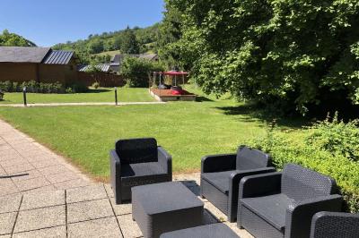 Chambre lumineuse avec lit double, bureau, télévision murale, fauteuil et fenêtre donnant sur l'extérieur.