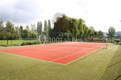 Chambre lumineuse avec lit double, bureau, télévision murale, fauteuil et fenêtre donnant sur l'extérieur.