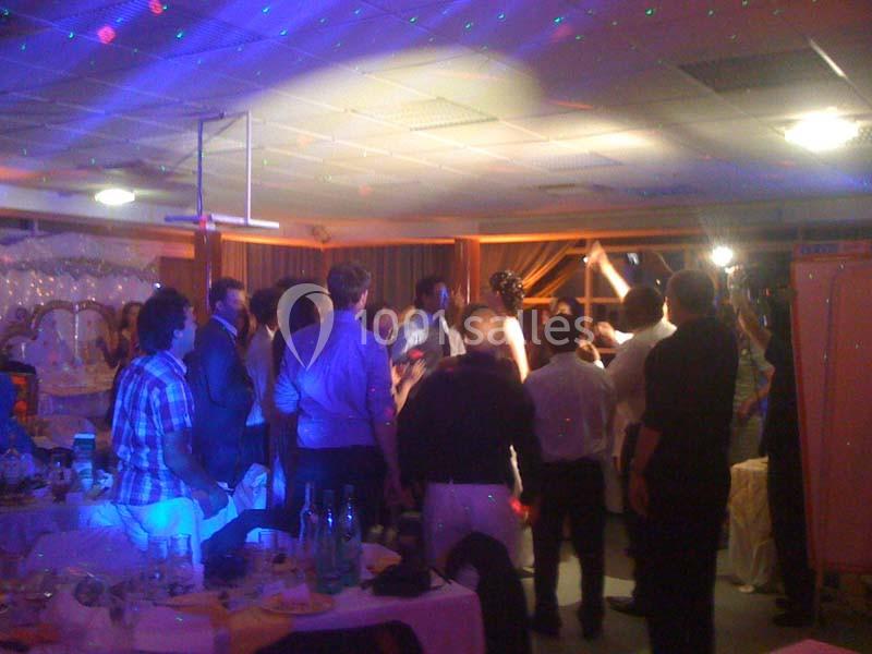 Groupe de personnes debout dans une salle éclairée, observant une scène festive sous des lumières colorées.