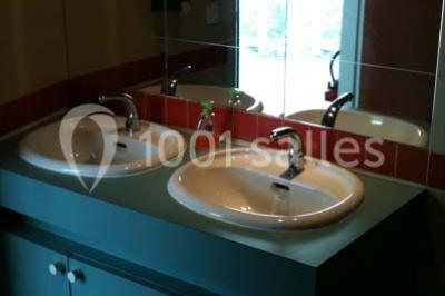 Vue nocturne depuis une fenêtre, montrant un parc éclairé, des arbres et des bâtiments en arrière-plan.