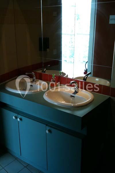 Deux lavabos blancs encastrés dans un meuble bleu, avec un miroir et une fenêtre en arrière-plan.