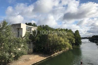 Vue nocturne depuis une fenêtre, montrant un parc éclairé, des arbres et des bâtiments en arrière-plan.