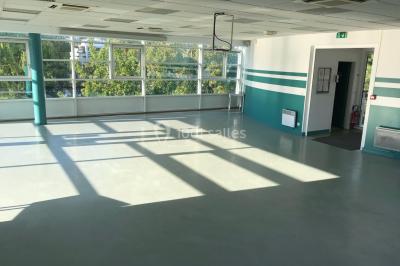 Vue nocturne depuis une fenêtre, montrant un parc éclairé, des arbres et des bâtiments en arrière-plan.