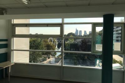 Vue nocturne depuis une fenêtre, montrant un parc éclairé, des arbres et des bâtiments en arrière-plan.