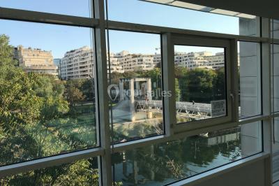 Vue nocturne depuis une fenêtre, montrant un parc éclairé, des arbres et des bâtiments en arrière-plan.