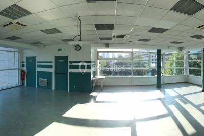 Vue nocturne depuis une fenêtre, montrant un parc éclairé, des arbres et des bâtiments en arrière-plan.