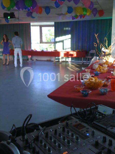 Salle décorée avec des ballons colorés, table garnie de snacks et console de mixage au premier plan.
