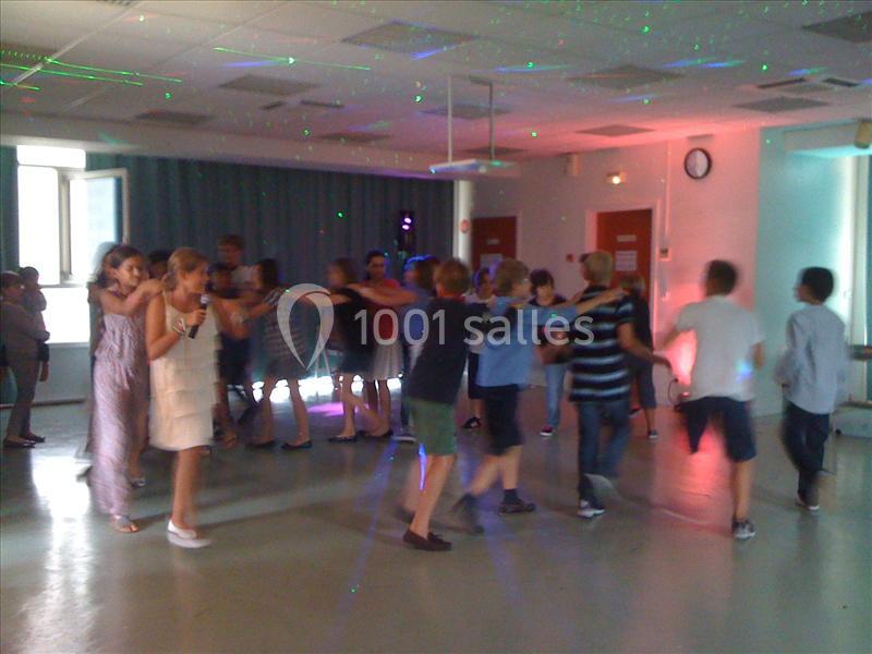 Des enfants dansent en chaîne dans une salle éclairée par des lumières colorées.