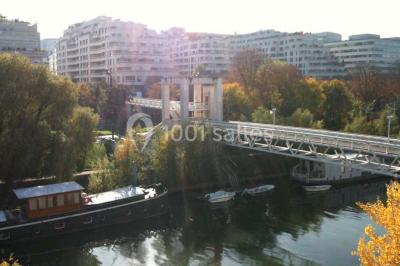 Salle vide avec sol clair, murs verts et blancs, grandes fenêtres, éclairage au plafond et mobilier minimal.